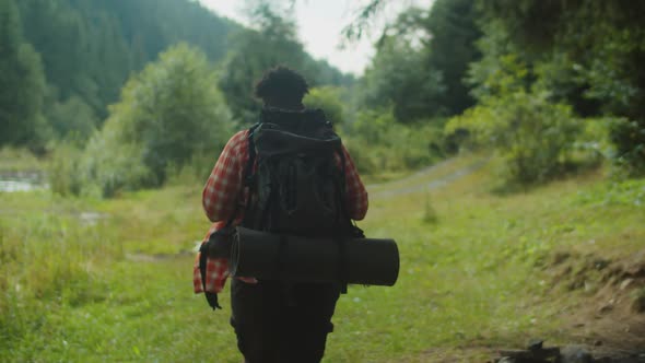 Handsome African American Man Hiker with Backpack Trekking Near Mountain River