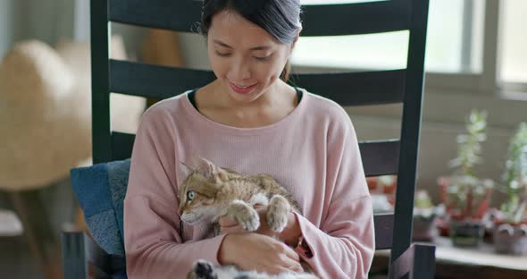 Woman cuddling cat at home