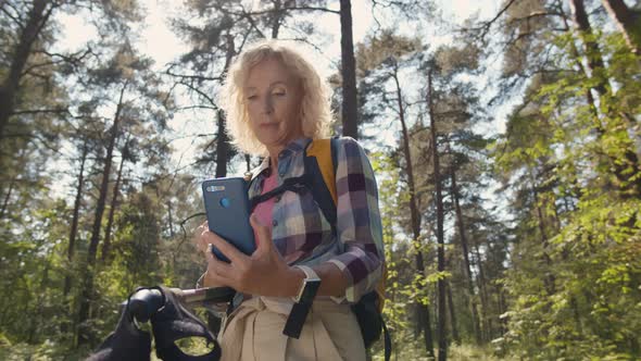 Senior Woman Hiker Using Smartphone While Enjoying Weekend in Forest