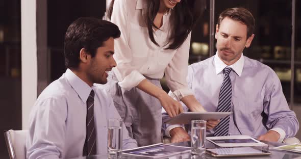 Businesswoman discussing with colleagues over digital tablet