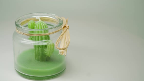 A Green Cactus Candle Formed Inside The Transparent Jar With Yellow Ribbon - Close Up Shot