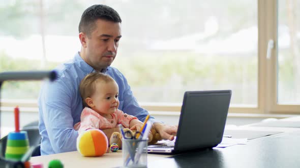 Father with Baby Working on Laptop at Home Office