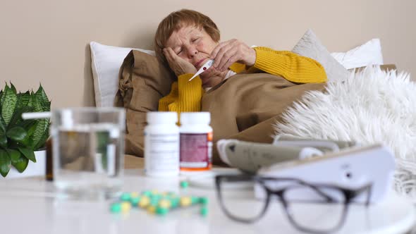 Sick Grandmother Checking Body Temperature With Thermometer.