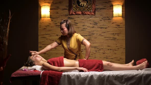 Thai massage in a cozy salon. Young woman on massage session