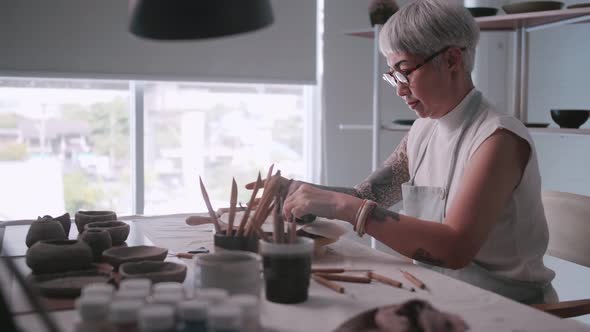 Asian elderly woman enjoying pottery work at home.