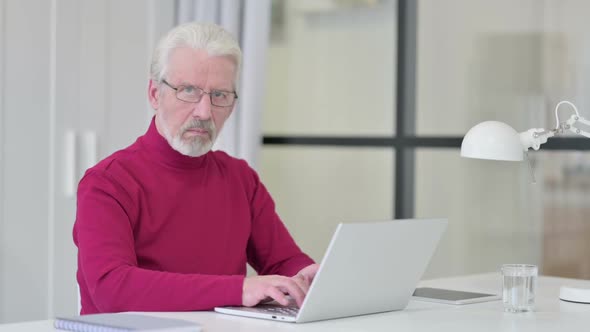 Thumbs Down By Old Man with Laptop at Work