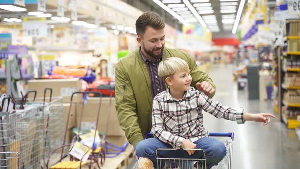 Kid Boy Point Finger at Side in Store During Shopping with Father