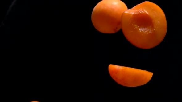 Halves Ripe Apricots Fly on a Black Background