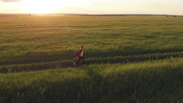 Happy Little Boy and Girl Runs Along Country Road Through a Beautiful Landscape of Green Hills at