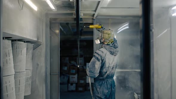 Worker in overalls and respirator paints.