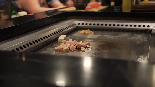 Asian Chef Slising Chicken Meat for the Audience on a Large Stove