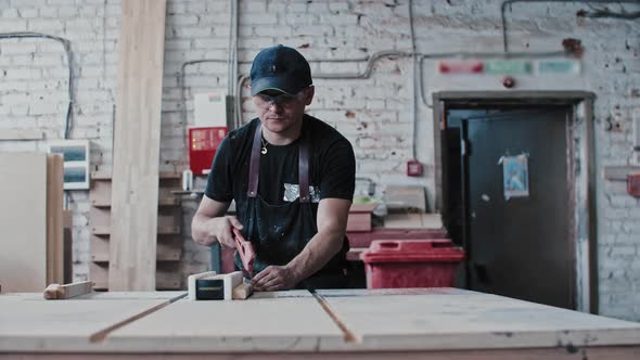 Man in Protective Glasses in Carpentry Workshop Cutting Pieces of a Small Wooden Detail Using a