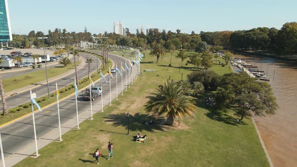 Aerial view flying fast by a coastal walk with an avenue beside and people hanging out