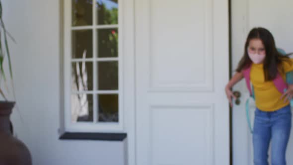 Caucasian girl wearing face mask with backpack standing outside the house