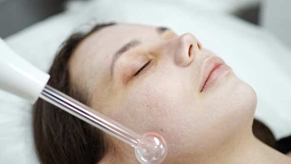 Beautician Uses the Darsonval Device on the Client's Face