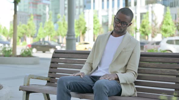 Tired African Man Sleeping While Sitting Outdoor on Bench