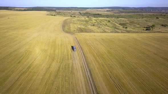 Aerial View of a Truck Driving on Dirt Road Between Plowed Fields Making Lot of Dust