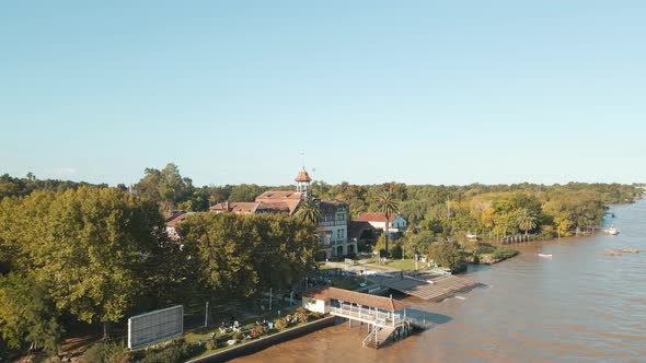 Aerial orbit of Tigre exclusive rowing club beside de la Plata river surrounded by trees at golden h