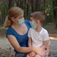Mother Hugs Her Son in Medical Masks While Sitting in a Park - VideoHive Item for Sale