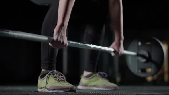 Anonymous Female Performs a Deadlift with Barbell Lifts Barbell and Does Weights Training in the Gym