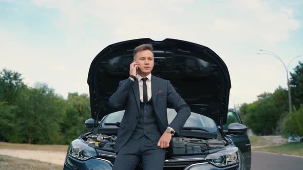 Young Man Using Smartphone Calling Car Assistance Services Standing By Breakdown Automobile