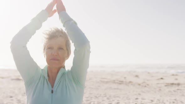 Senior woman performing yoga in the beach