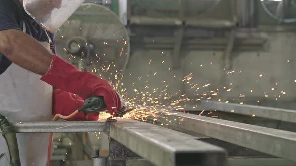 Slow motion of a worker using metal grinder with sparks flying at a metal shop