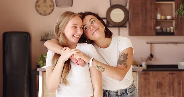 Two women friends hugging at home. Adorable lesbian couple.