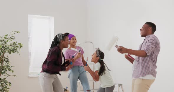 Crazy Happy Family Dances in Middle of Room During Break From Painting the Walls a Woman and Her