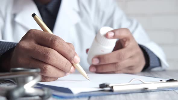 Doctor Hand Writing Prescription on Desk Close Up