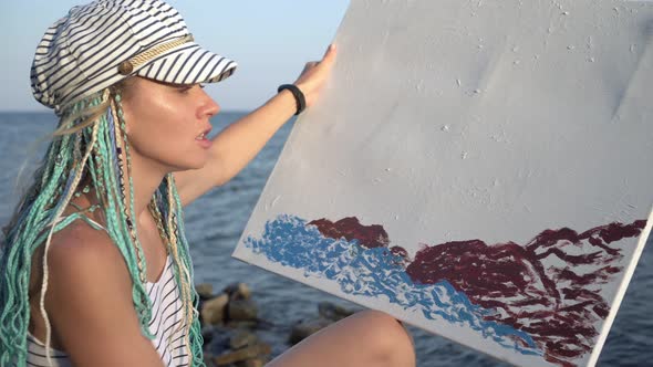 Attractive Woman Artist Paints the Sea on Canvas