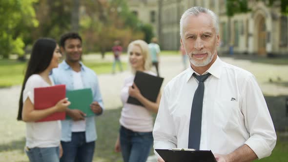 Professor and Students Standing Near University, Dean Looking Into Camera