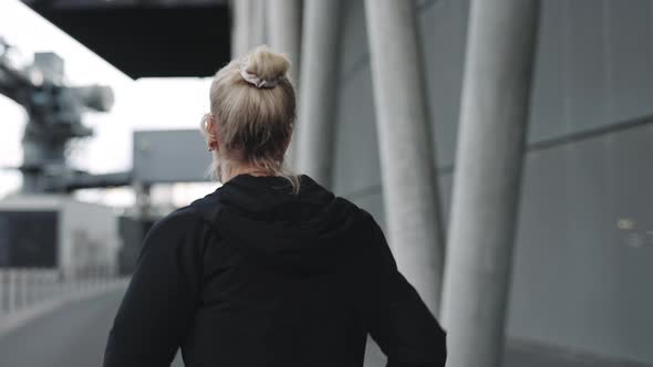 Back View of Mature Woman Running Along City Street