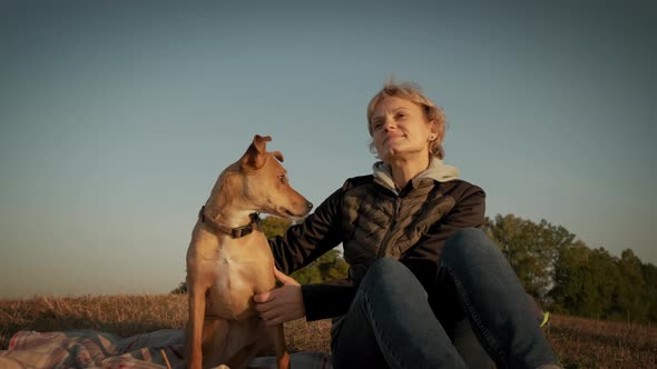 Woman Sitting with a Dog During Sunset