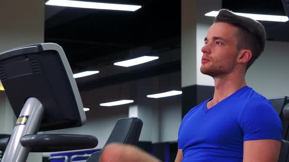 A Young Fit Man Trains on a Recumbent Bike in a Gym - Closeup