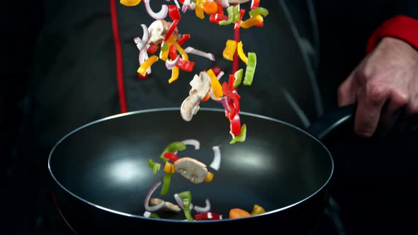 Super Slow Motion Shot of Chef Holding Frying Pan and Falling Vegetables at 1000Fps