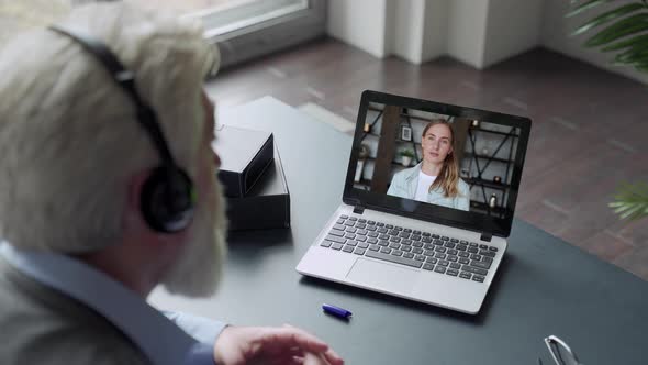 Over the Shoulder View of an Elderly Man Video Call To Daughter Using a Laptop. The Concept of