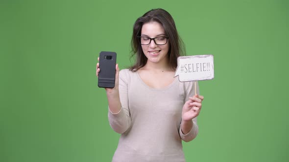 Young Happy Beautiful Woman Holding Phone and Selfie Paper Sign