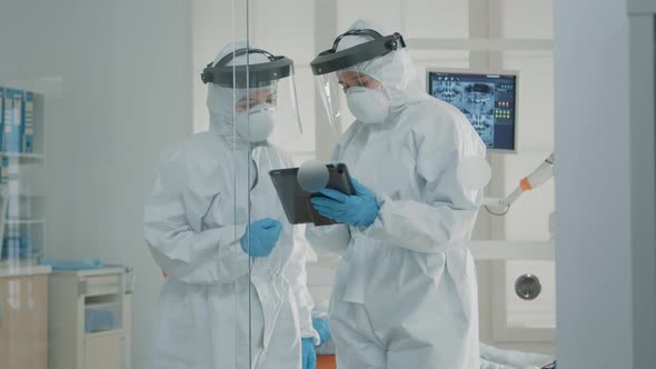 Orthodontists Wearing Protection Suits Looking at Tablet