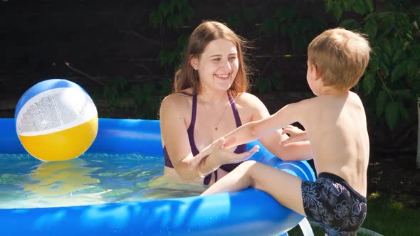 Little Smiling Boy Climbing in Inflatable Swimming Pool on House Backyard and Playing with Young