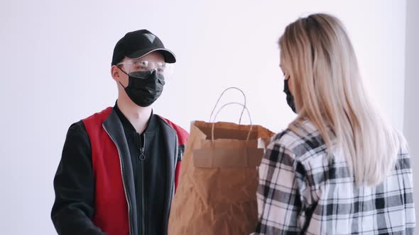 Deliveryman Is Diving a Craft Paper Bag To a Woman in Mask