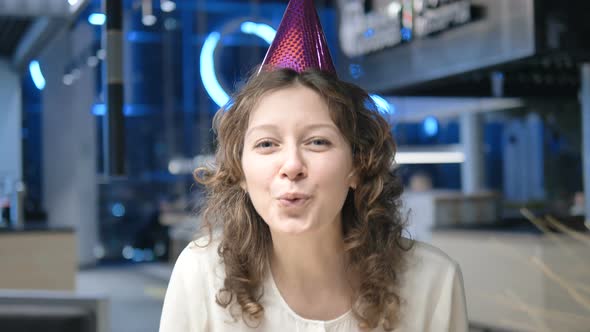 Woman with Cone on Head Blows To Camera Claps and Smiles