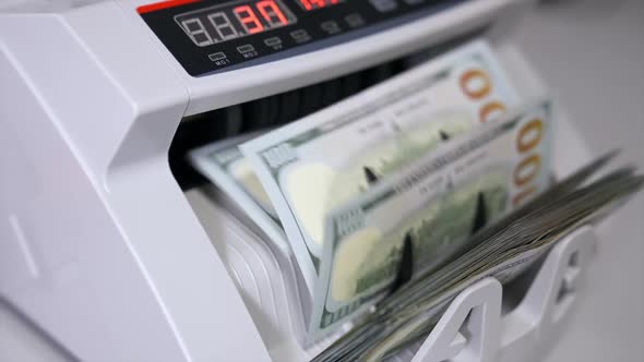 Electronic money counter machine is counting is counting the American hundred-dollar banknotes.