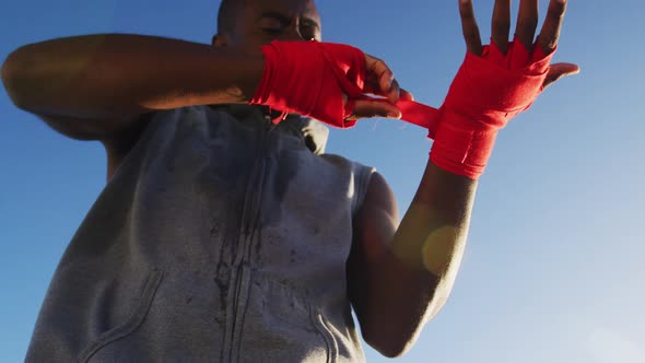 Focused african american man wrapping his hands, exercising outdoors