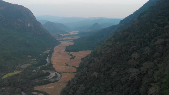 Aerial: flying over rice paddies unique valley scenic cliffs rock pinnacles tropical jungle stunning