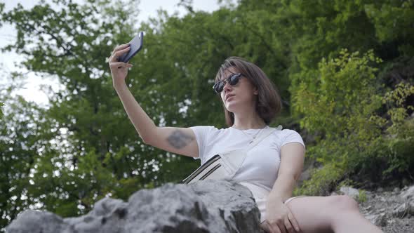 Caucasian Female Tourist Taking Selfie on a Rock on the Mountain.