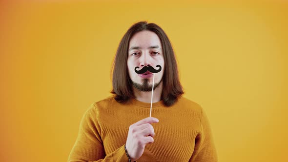 Studio Portrait of Caucasian Bearded Man in Disguise Created By Fake Paper Moustache