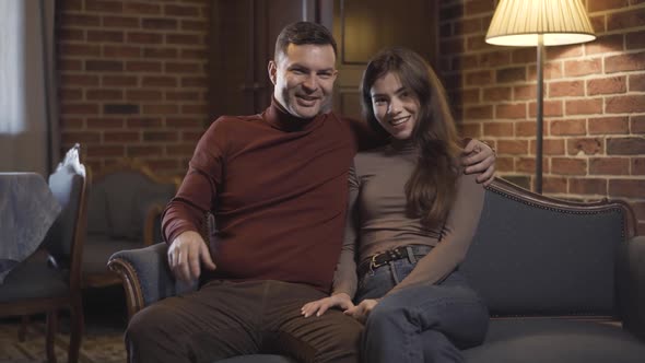 Positive Hugging Couple Sitting in Living Room Watching TV