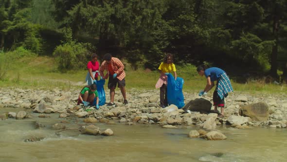 Eco Friendly Diverse Multicultural Volunteers Picking Up Plastic Waste During Cleanup at Riverbank