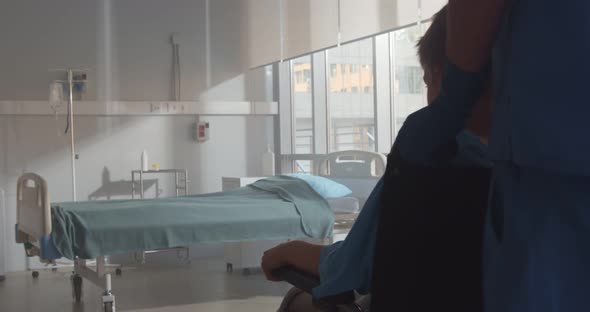 Cropped Shot of Nurse Pushing Sick Boy in Wheelchair in Hospital Ward